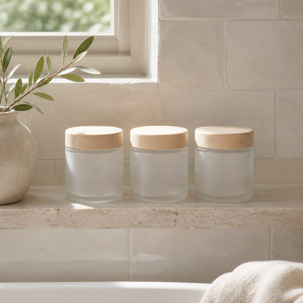 Apothecary jars lined up on a stone bathroom shelf