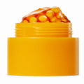 Open golden orange capsule cream jar with orange capsules