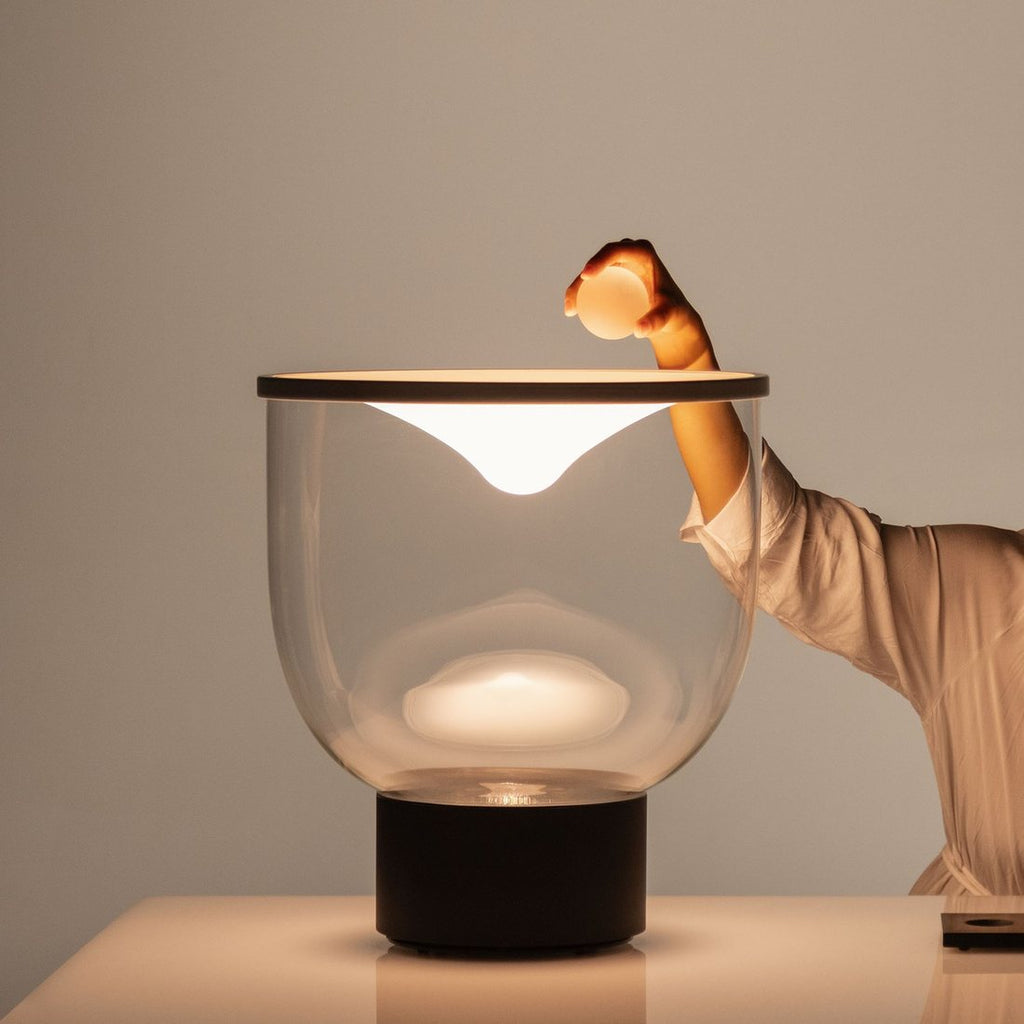 A hand setting a glass sphere onto the lamp