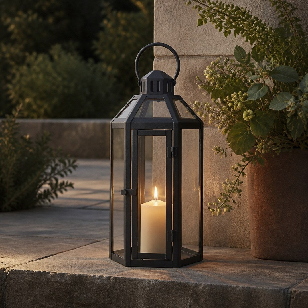 Glass garden lantern lit on a stone patio step at dusk