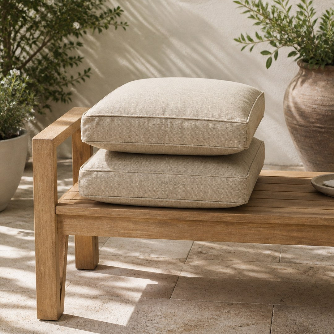 Outdoor cushions on a teak bench on a stone patio