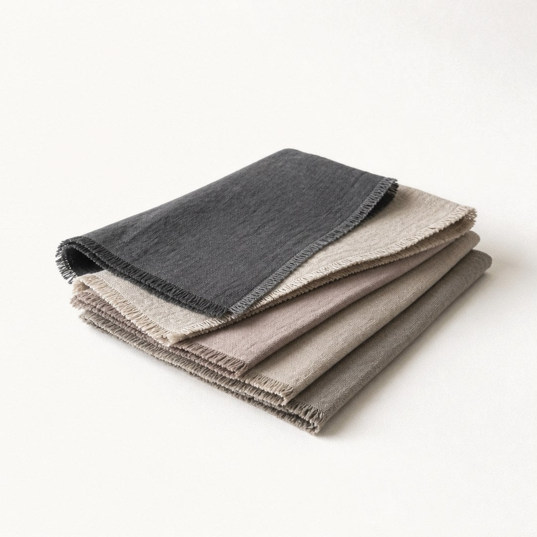 Set of four linen placemats fanned in a stack showing stitched edges