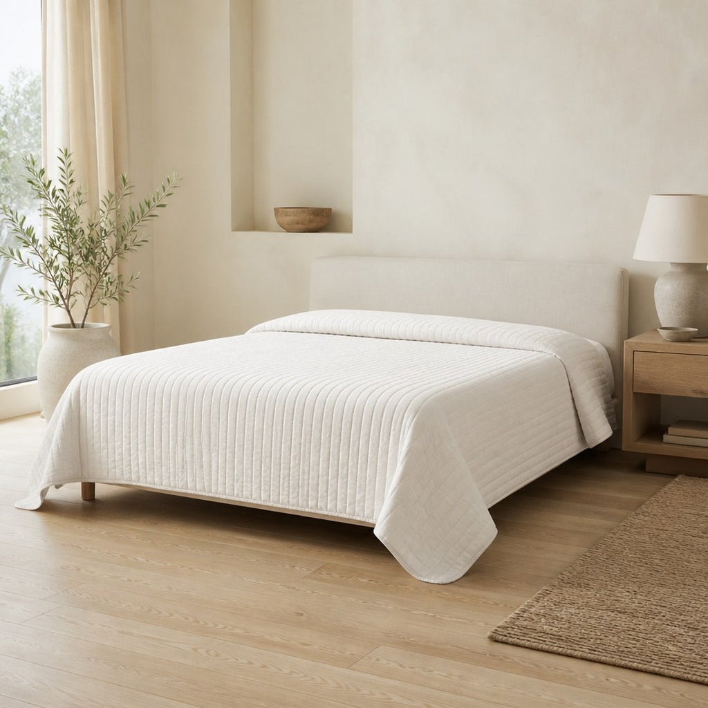 Quilted bedspread over a low bed in a bright bedroom