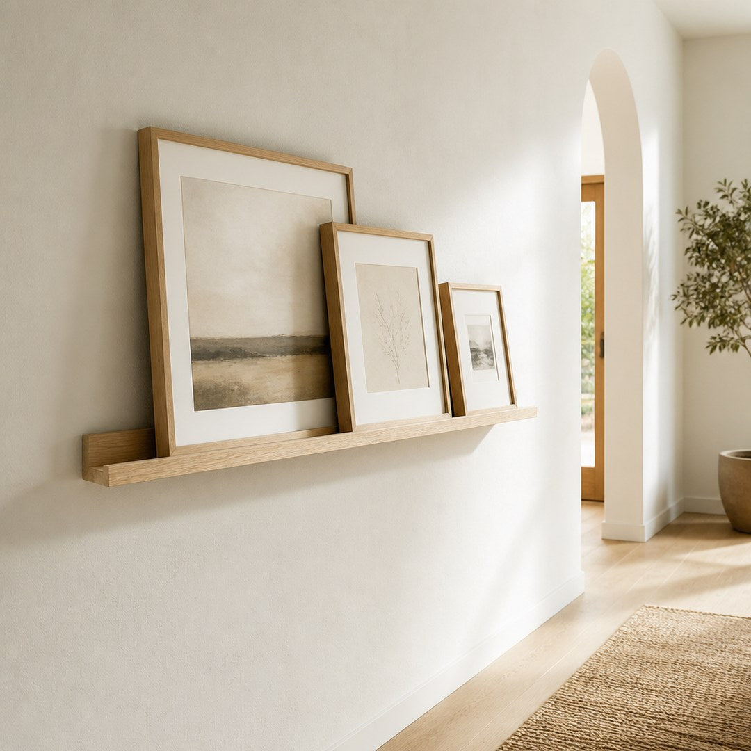 Picture ledge mounted in a hallway holding leaning framed prints