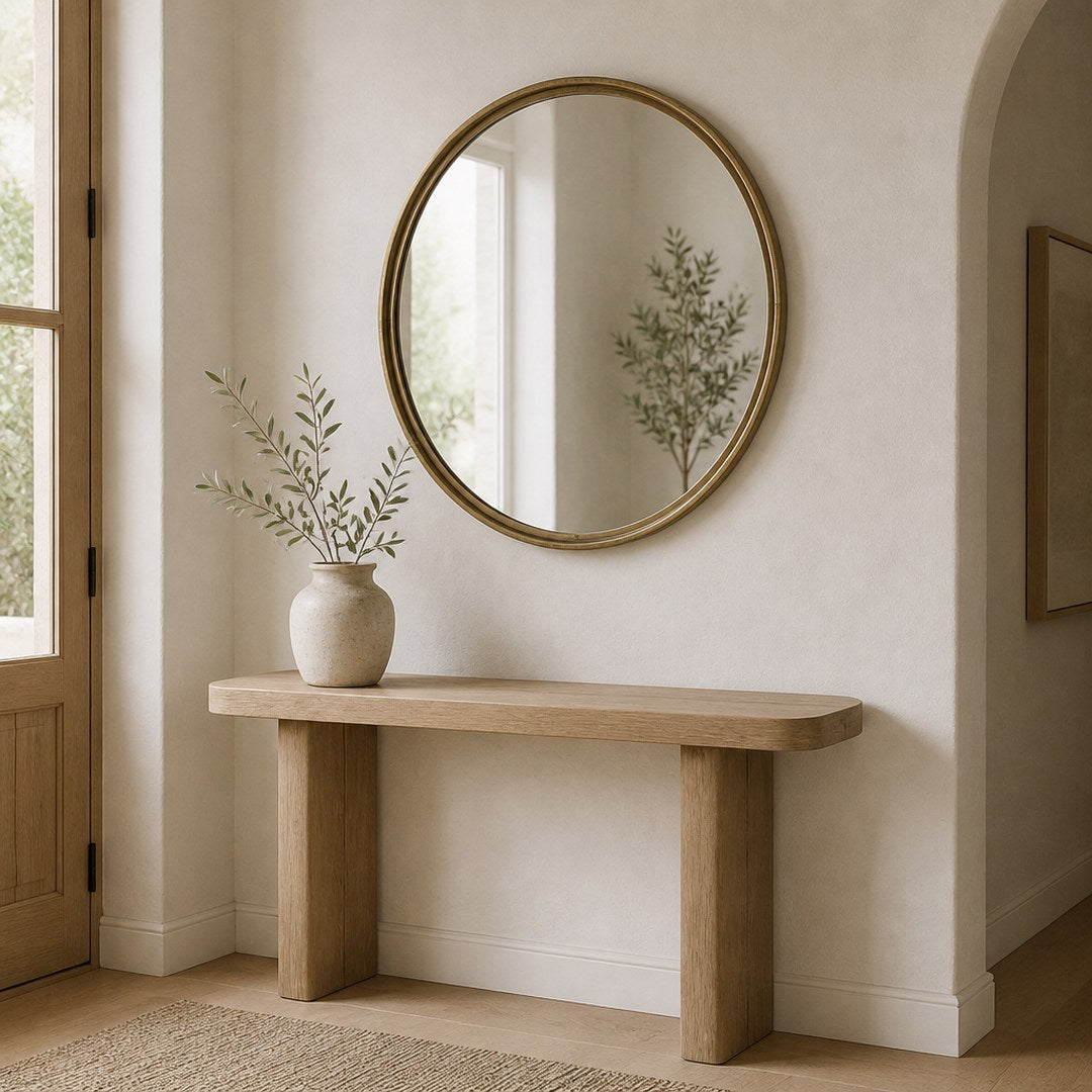 Round brass mirror hung above an entryway console table