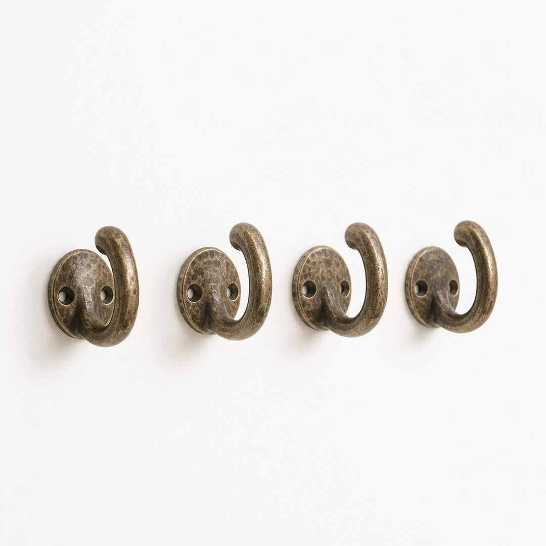 Four brass wall hooks laid out separately showing the mounting plate